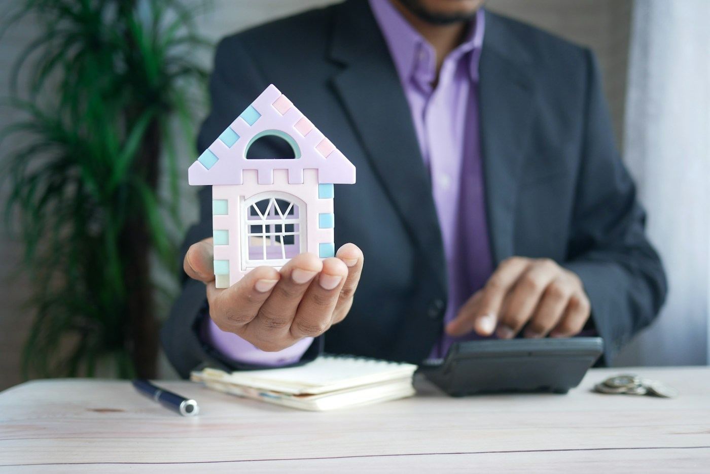 Investisseur avec une maquette de maison et une calculatrice